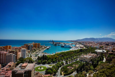 High angle view of townscape by sea against clear blue sky