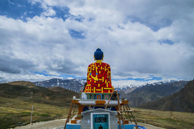 Rear view of cross against cloudy sky