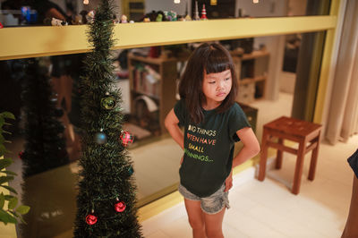 Full length of girl standing in christmas tree