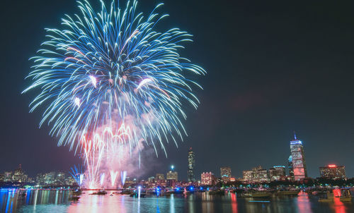 Firework display in city against sky at night