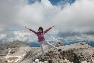 Full length of woman with arms outstretched standing on mountain against sky