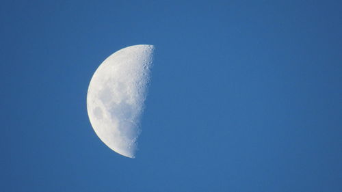 Low angle view of moon against clear blue sky