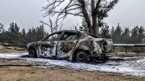 Abandoned car on land against sky