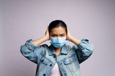 Portrait of young woman standing against wall