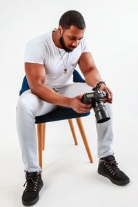 Full length of young man sitting against white background