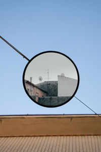 Low angle view of building against clear sky mirrored in street lamp