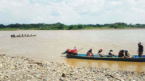 People in boat on river against sky