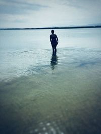 Rear view of man in sea against sky