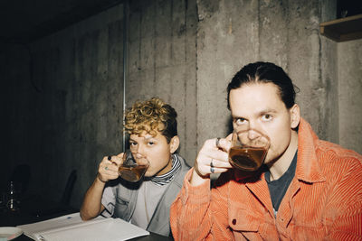 Portrait of smiling entrepreneurs drinking coffee while sitting in creative office