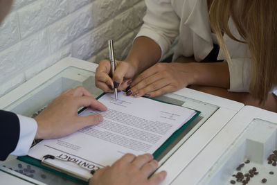 Midsection of businesswoman signing contract with male colleague in office