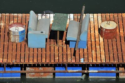 High angle view of old sofas and drums on pier over lake