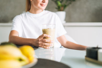 Midsection of woman holding drink on table