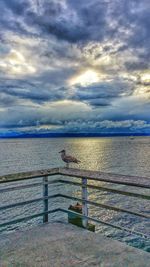 Pier on sea against cloudy sky