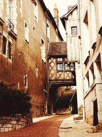 Alley amidst houses against sky