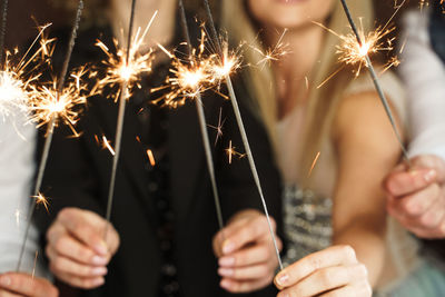 Midsection of woman holding sparkler at night