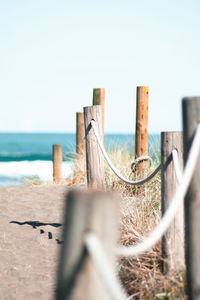 Close-up of wooden fence by sea against clear sky