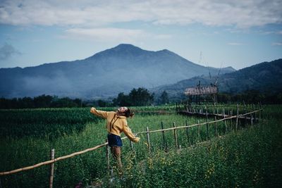 Smiling woman standing on field against sky