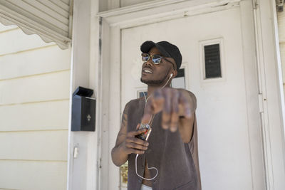 Young man listening to music at his front door