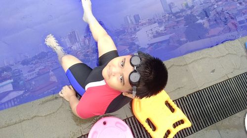 High angle portrait of cute boy sitting on poolside