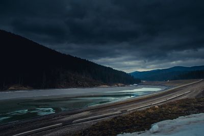 Scenic view of mountains by sea against cloudy sky