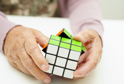 Cropped hand of woman holding toy blocks against white background
