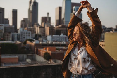 Midsection of woman standing by buildings in city against sky