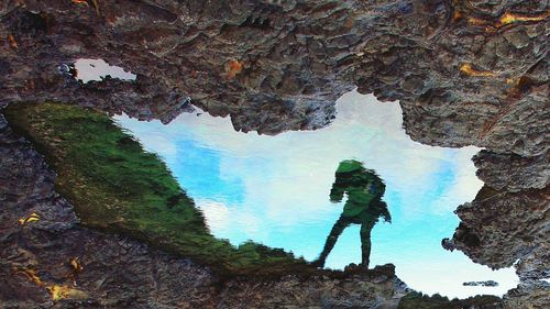 Man standing on rock formation against sky