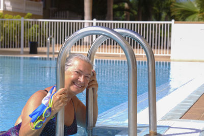 Portrait of smiling senior woman by swimming pool