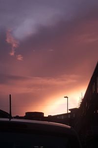 Car on silhouette road against sky during sunset