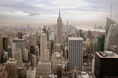 Aerial view of city buildings against cloudy sky