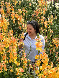 Young woman standing amidst yellow flowering plants