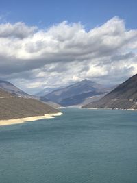 Scenic view of sea and mountains against sky rever