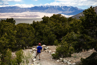 Rear view of boy walking on mountain against sky