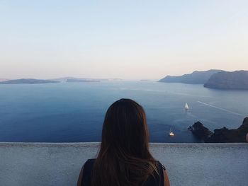 Rear view of woman standing by lake against sky