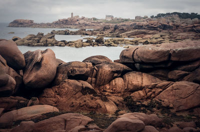 Rocks at sea shore against sky