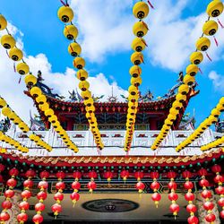 Illuminated lanterns hanging by building against sky