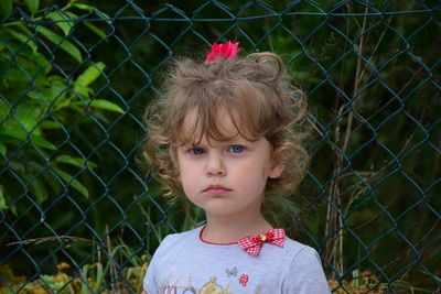 Portrait of cute girl standing against chainlink fence