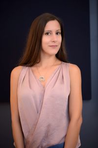 Portrait of smiling young woman standing against wall