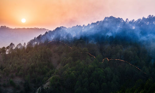 Scenic view of tree mountains against sky during sunset