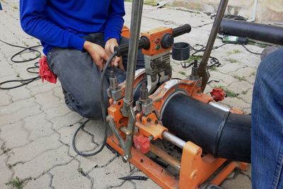 Midsection of man crouching by machinery on footpath