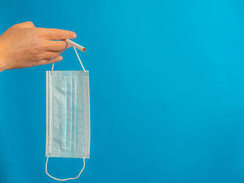 Close-up of person hand against blue background