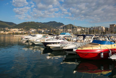 Boats moored at harbor against sky