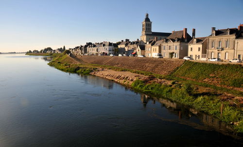 Buildings by river against sky in city