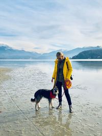 Full length of woman with dog standing at lake