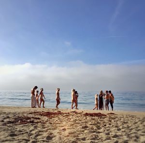 People walking at sea shore against sky
