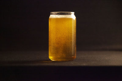 Close-up of beer glass on table against black background