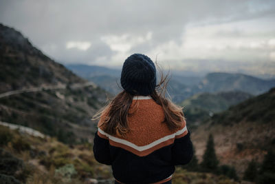 Rear view of woman looking at mountains against sky