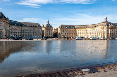 Buildings at waterfront against cloudy sky