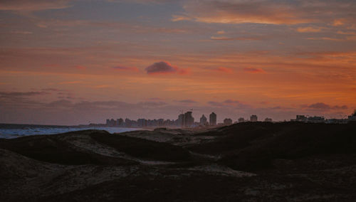 Scenic view of sea and buildings against sky during sunset