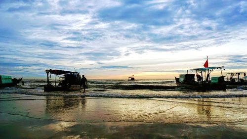 Boat moored on beach against sky